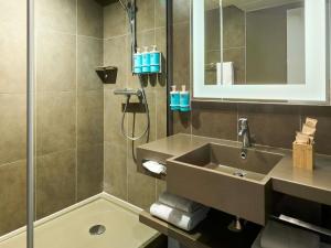 a bathroom with a sink and a shower at Novotel Paris La Defense Esplanade in Courbevoie