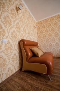a brown leather chair in a room with wallpaper at Cozy flat apartment in Chişinău