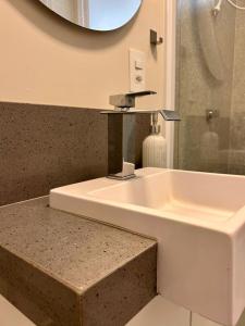 a bathroom with a sink and a mirror at Apto estúdio na praça central in Serra Negra +26 photos