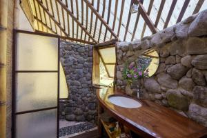 a bathroom with a sink and a stone wall at Vanira Lodge in Teahupoo +110 photos