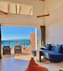 a living room with a blue couch and a view of the ocean at Love&Peace Resort in Shima