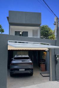 a car is parked in a garage in front of a house at Casa do Sol - 300M da Praia - Ar condicionado in São Pedro da Aldeia