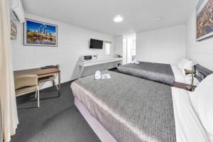 a hotel room with two beds and a desk at Bendigo Motor Inn in Bendigo