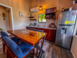 a kitchen with a wooden table and a refrigerator at House Monstera Arenal in Agua Azul