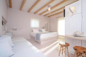 a white bedroom with a bed and a table at Antony Suites (Adults Only) in Naxos Chora