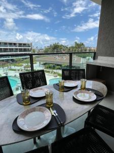 a table with plates and glasses on a balcony at Beach Class Verano 214 C in Ipojuca