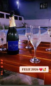 a bottle of wine and four wine glasses on a table at Villa Mediterraneo in Beberibe
