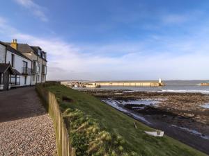 a house on the beach with a pier in the background at Corner Cottage in Seahouses