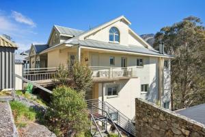 a white house with a stone wall at Inala 2 in Thredbo