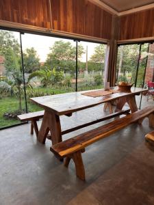 a picnic table and benches in a room with windows at Alojamiento Mariana y Ocho Oñondive in Villa Concepción
