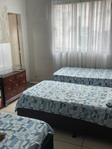 a bedroom with two beds and a dresser and window at Palace Hotel in Anápolis +8 photos