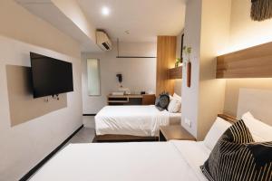 a hotel room with two beds and a flat screen tv at Hotel NuVe in Singapore