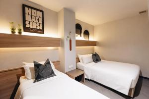 two beds in a room with white sheets at Hotel NuVe in Singapore