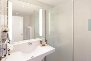 a white bathroom with a shower and a sink at Novotel Porto Gaia in Vila Nova de Gaia