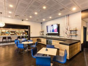 a restaurant with tables and chairs and a flat screen tv at Novotel Genova City in Genoa