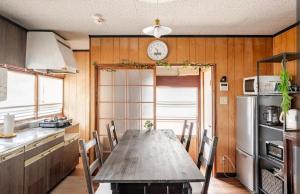 a kitchen with a table with chairs and a clock on the wall at 古民家おにぎり in Otsu
