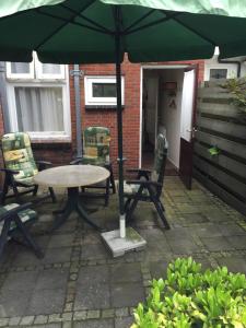 een tafel en stoelen onder een parasol op een patio bij Vakantiehuisje in Centrum Ootmarsum in Ootmarsum