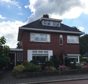 een rood bakstenen huis met witte ramen en struiken bij Vakantiehuisje in Centrum Ootmarsum in Ootmarsum