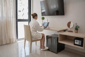 a woman sitting at a desk with a laptop at Alcaré Rooms Cartagena in Cartagena de Indias