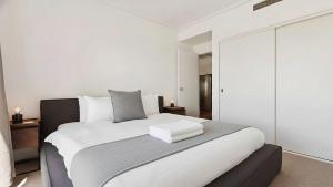 a bedroom with a large white bed with white pillows at Stylish Apartment in Melbourne +9 photos
