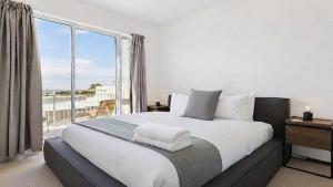 a bedroom with a large bed and a large window at Stylish Apartment in Melbourne