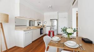 a kitchen with a wooden table and white cabinets at Stylish Apartment in Melbourne