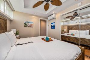 a bedroom with a large white bed with a ceiling fan at Lahaina Roads 209 in Lahaina +45 photos