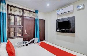 a bedroom with a bed and a tv and a table at Gold Hotel in Faridabad