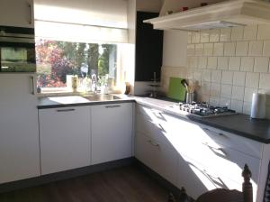 a kitchen with white cabinets and a sink and a window at Hezebergzicht in Groot-Agelo