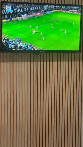 a television on a wall with a soccer game on it at Pousada O Leão in Piaçabuçu