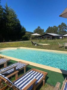 a swimming pool with lounge chairs and a house at Cabañas Ruta Lacustre in Licán Ray