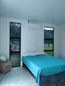 a bedroom with a blue bed and two windows at Cabaña Moderna a 1km del Centro de Tauramena in Tauramena +80 photos
