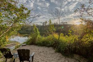 a bench sitting on the sand next to a river at Batiscan - Waterfront Private Spa & Sauna in Saint Adelphe