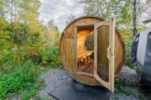 a wooden sauna with a wooden table in the woods at Batiscan - Waterfront Private Spa & Sauna in Saint Adelphe