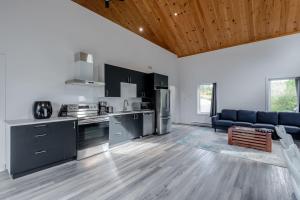 a kitchen with black cabinets and a blue couch at Batiscan - Waterfront Private Spa & Sauna in Saint Adelphe +30 photos