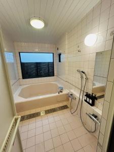 a bathroom with a bath tub and a window at HARMONIA 那須 Nas-MAX26名-川遊び-BBQ-カラオケのできる宿 in Nasu +64 photos