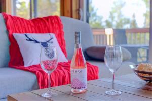 two wine glasses and a bottle on a wooden table at L'Enchanteur - Private Spa & Pet Friendly in Pohénégamook