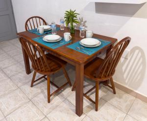 a wooden table with four chairs and a table with plates at Casa San Luis in Tuxtla Gutiérrez