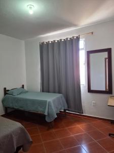 a bedroom with a bed and a window with a curtain at Suite confort 02 in Contagem