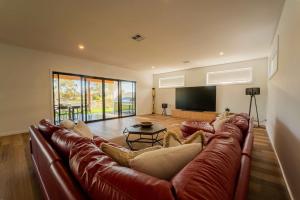 a living room with a leather couch and a flat screen tv at 10 Jefferson Court in Wellington East