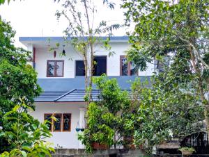 a white house with trees in front of it at Blooms home stay in Thekkady