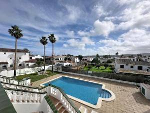 a swimming pool in a yard with palm trees at Apartamento con piscina SS19 in Fornells