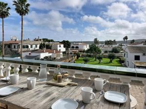 a wooden table with plates and cups on a balcony at Apartamento con piscina SS19 in Fornells