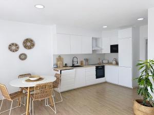 a kitchen with white cabinets and a table and chairs at Apartamento con piscina SS19 in Fornells +16 photos