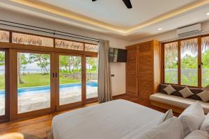 a bedroom with a bed and a couch and a pool at Villa Madu Mentawai in Katiet +50 photos