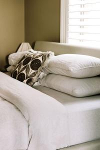 a stack of white pillows on a bed with a window at The Brewers House in Beechworth +48 photos