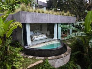 a bed in a glass house with a swimming pool at Utopia Concept Bali - Adults Only in Ubud