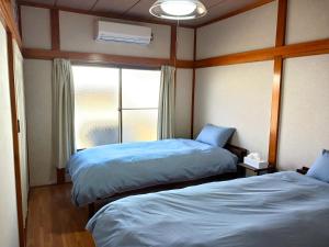 two beds in a room with a window at GuestHouseさがら丸 in Niijimamura