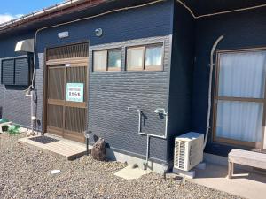 a blue house with a cat sitting in front of it at GuestHouseさがら丸 in Niijimamura