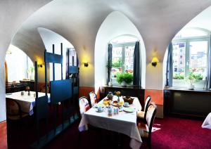 バウツェンにあるHotel Goldener Adlerの白いテーブルと椅子、窓のあるレストラン